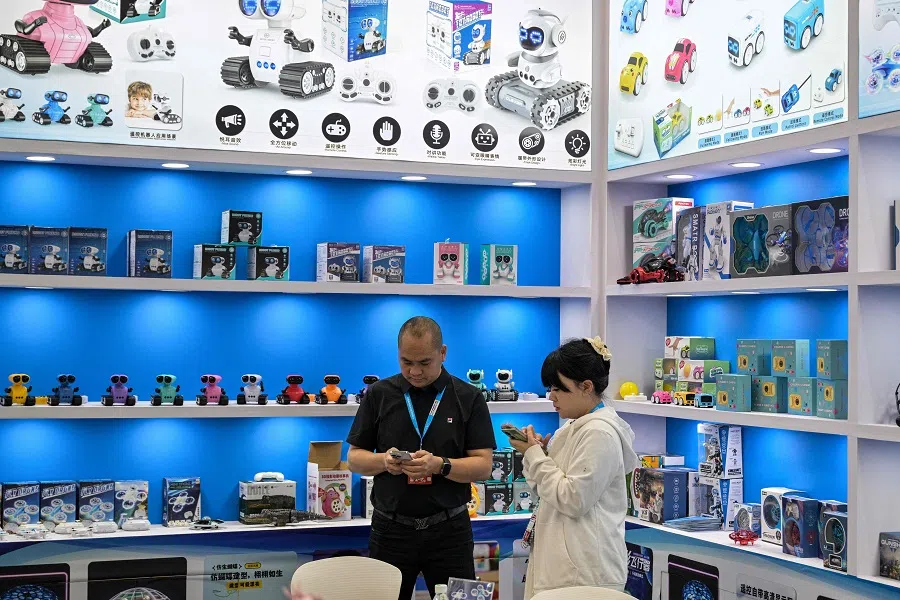 Promoters use their phone in their stand at the Ningbo Cross-Border E-commerce Expo Fair in Ningbo, in China’s eastern Zhejiang Province on 29 May 2025. (Hector Retamal/AFP)