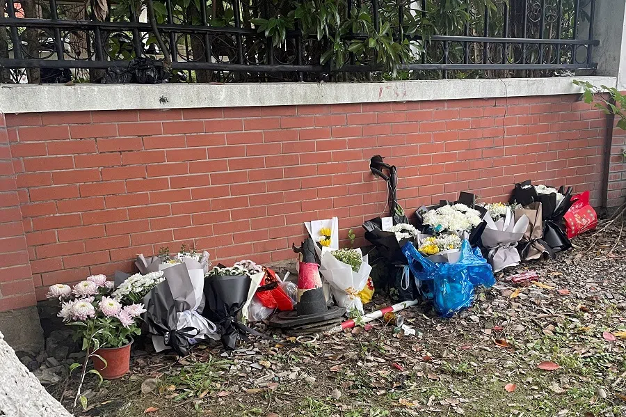 Floral tributes are placed near an entrance to the Wuxi Vocational College of Arts and Technology following a knife attack, in Wuxi, Jiangsu province, China, on 17 November 2024. (Brenda Goh/Reuters)