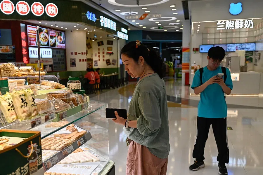 A woman shops at a store insides a shopping mall in Beijing, 4 August 2024. (Pedro Pardo/AFP)