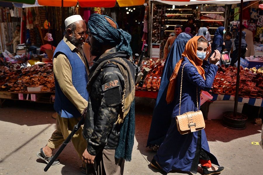 A Taliban fighter (centre) walks past shoppers along Mandawi market in Kabul on 1 September 2021. (Hoshang Hashimi/AFP)