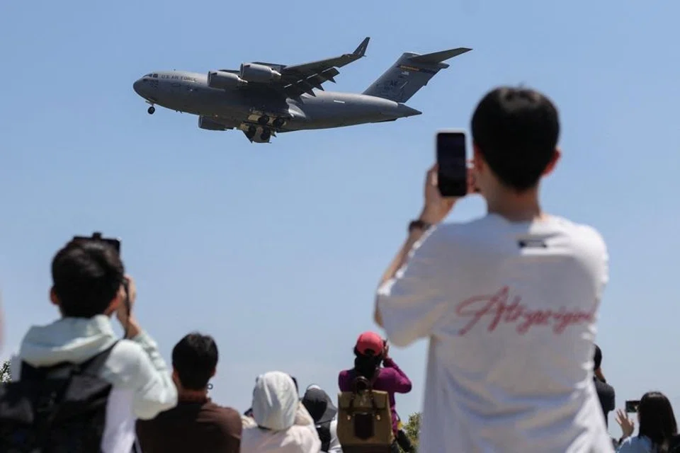 People use their phones as a US Air Force C-17A Globemaster III lands at Beijing Capital International Airport, ahead of US President Donald Trump's state visit to China, in Beijing, China, on 11 May 2026. (Tingshu Wang/Reuters)