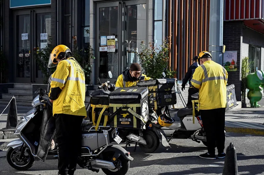 This photo taken on 19 October 2021 shows food delivery drivers for online shopping platform Meituan resting along a street in Beijing, China. (Jade Gao/AFP)