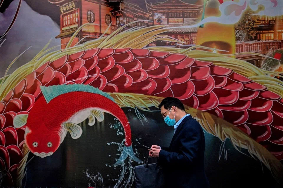 In a digital age, panic-inducing information can spread even faster than viruses. In the photograph, a man wearing a facemask as a preventive measure against Covid-19 checks his mobile phone at Yu Garden in Shanghai on 23 March 2020. (Hector Retamal/AFP)