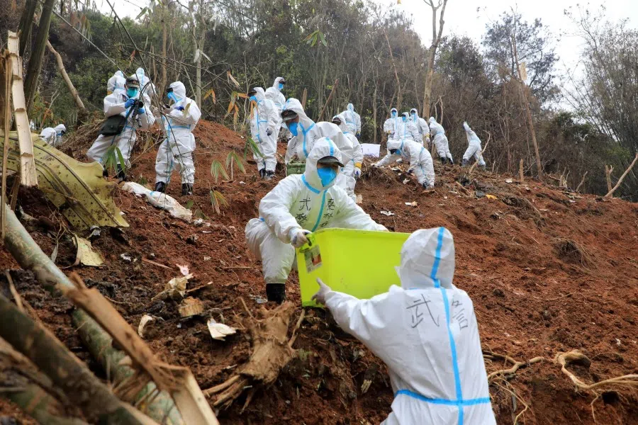 This photo taken on 26 March 2022 shows paramilitary police officers transferring fragments of the wreckage of the China Eastern passenger jet which crashed onto a mountainside in Tengxian county, Wuzhou city, in China's southern Guangxi region. (CNS/AFP)