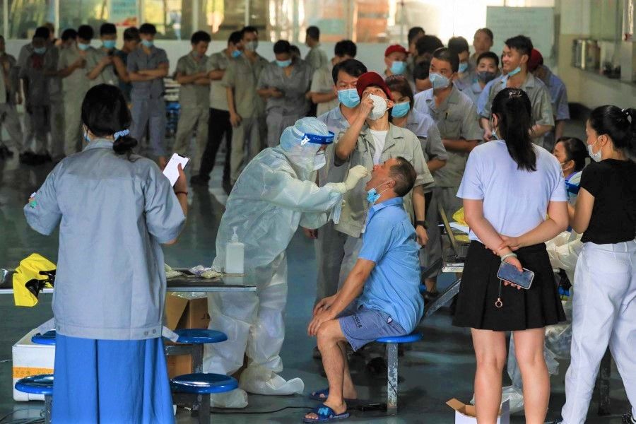 A worker receives a nucleic acid test for the Covid-19 coronavirus at the dining hall of a car parts factory in Wuhan, in China's central Hubei province on 4 August 2021. (STR/AFP)