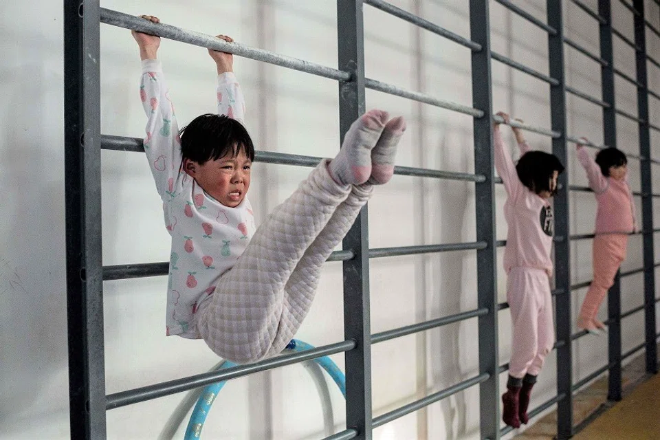 In this picture taken on 11 January 2021, young gymnasts train at the Li Xiaoshuang Gymnastics School in Xiantao, Hubei province, China. (Nicolas Asfouri/AFP)