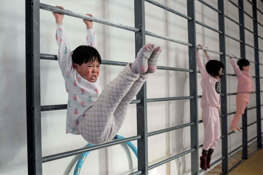 In this picture taken on 11 January 2021, young gymnasts train at the Li Xiaoshuang Gymnastics School in Xiantao, Hubei province, China. (Nicolas Asfouri/AFP)