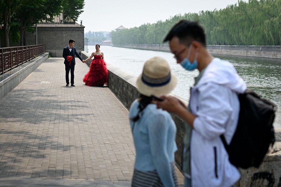 A couple (back) poses for wedding photos near the Forbidden City in Beijing, China, on 20 May 2021. (Wang Zhao/AFP)