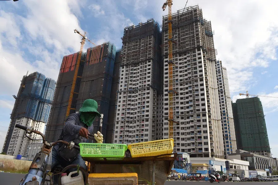 A vendor grills bananas across buildings under construction in Phnom Penh, Cambodia, on 6 January 2021. (Tang Chhin Sothy/AFP)
