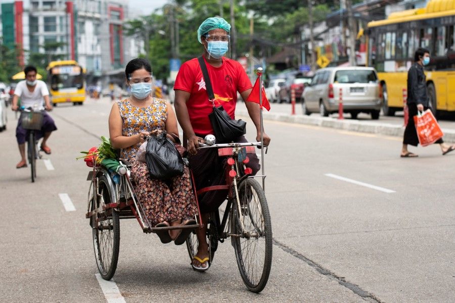 A trishaw driver drives a woman while both wear face mask amid the coronavirus disease (Covid-19) spread, in Yangon, Myanmar, 2 October 2020. (Shwe Paw Mya Tin/REUTERS)