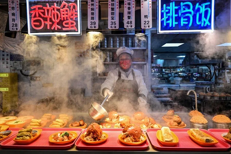 A food seller prepares dishes at a restaurant at Yu Garden in Shanghai on 21 January 2026. (Hector Retamal/AFP)