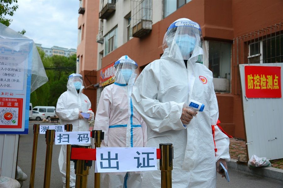 Volunteers in protective suits are seen at a checkpoint at the entrance of a residential compound following the Covid-19 outbreak, in Jilin, China, on 25 May 2020. (China Daily via Reuters)