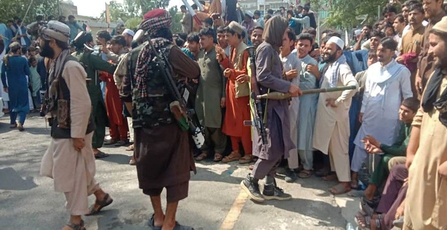 Taliban fighters and local people are pictured along the street in Jalalabad province, Afghanistan on 15 August 2021. (AFP)