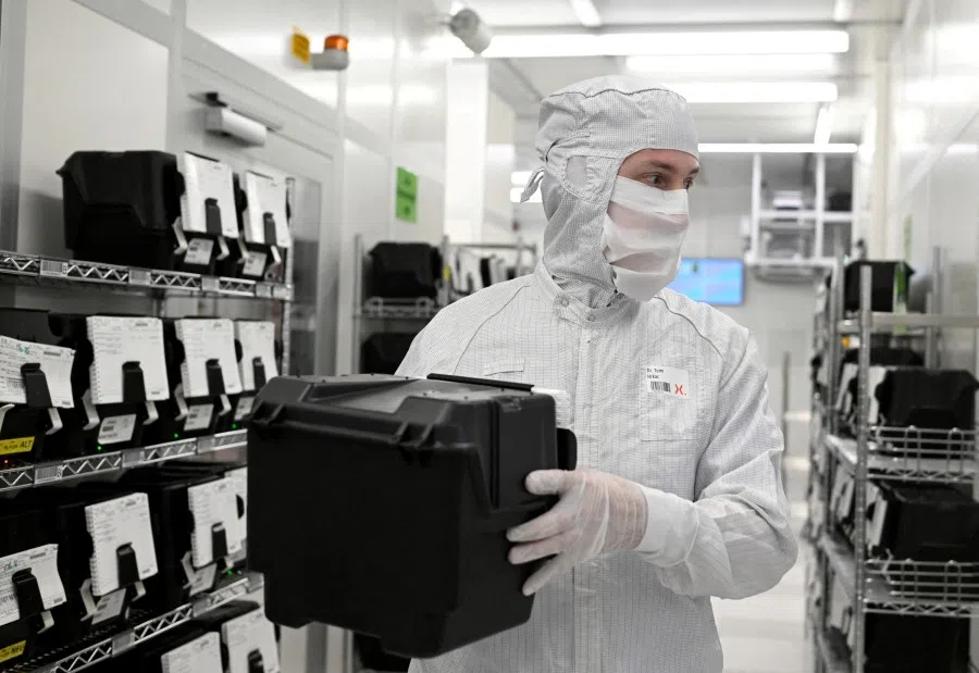 An employee holds a box with wafers in a production line of Dutch semiconductor company Nexperia, in Hamburg, Germany, 27 June 2024. (Fabian Bimmer/Reuters)