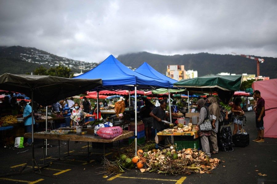Customers buy groceries at a market in Saint-Denis de la Reunion on the French Indian Ocean island of La Reunion on 25 February 2022. (Christophe Archambault/AFP)