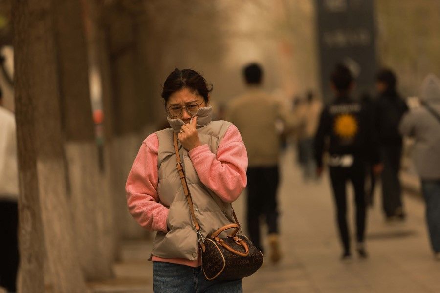 A woman walks on a street during a sandstorm in Shenyang, in China's northeastern Liaoning province on 11 April 2023. (AFP)