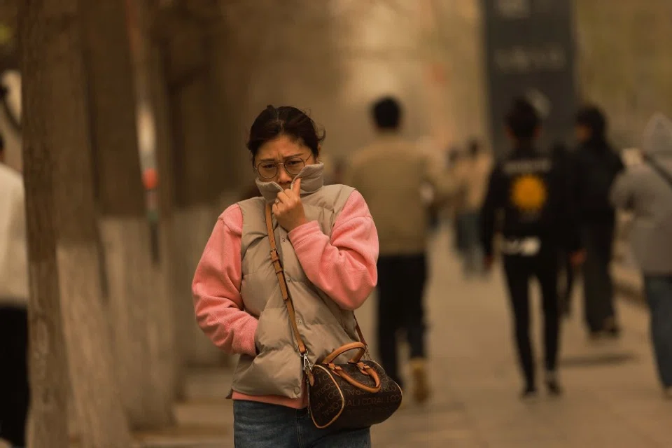 A woman walks on a street during a sandstorm in Shenyang, in China's northeastern Liaoning province on 11 April 2023. (AFP)