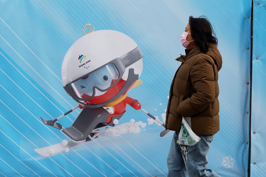 A woman walks past a display of a Beijing 2022 Olympic mascot near a flagship merchandise store for the Beijing 2022 Winter Olympics in Beijing, China, 8 December 2021. (Carlos Garcia Rawlins/Reuters)
