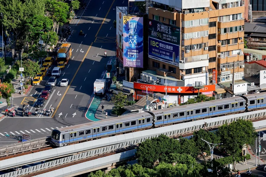 A metro train passes through the city as vehicles wait at a traffic light in Taipei, Taiwan, 2 October 2025. (Ann Wang/Reuters)
