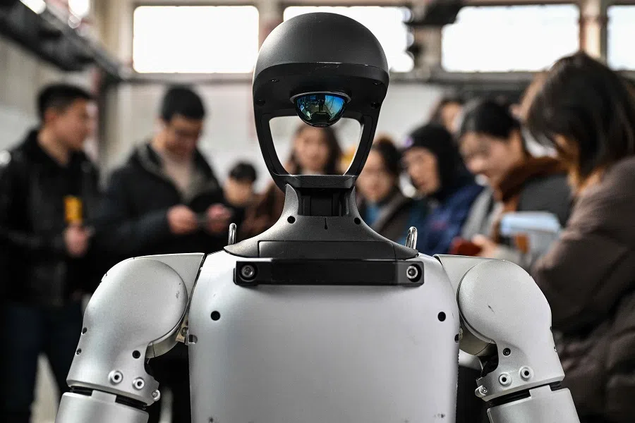People stand next to a humanoid robot from Unitree Robotics during the Global Developer Conference, organised by the Shanghai AI Industry Association, in Shanghai, China, on 21 February 2025.
