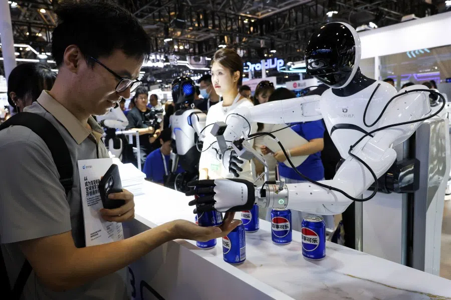 A person receives a can of soda from a humanoid robot at an Agibot booth during the World Artificial Intelligence Conference in Shanghai, China, 26 July 2025.