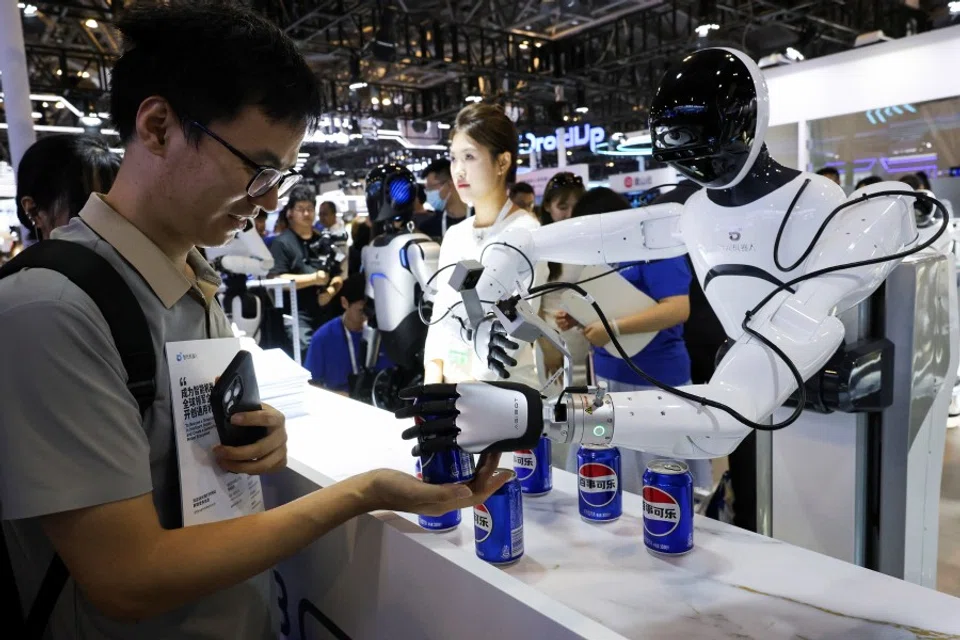 A person receives a can of soda from a humanoid robot at an Agibot booth during the World Artificial Intelligence Conference in Shanghai, China, 26 July 2025. (Go Nakamura/Reuters)