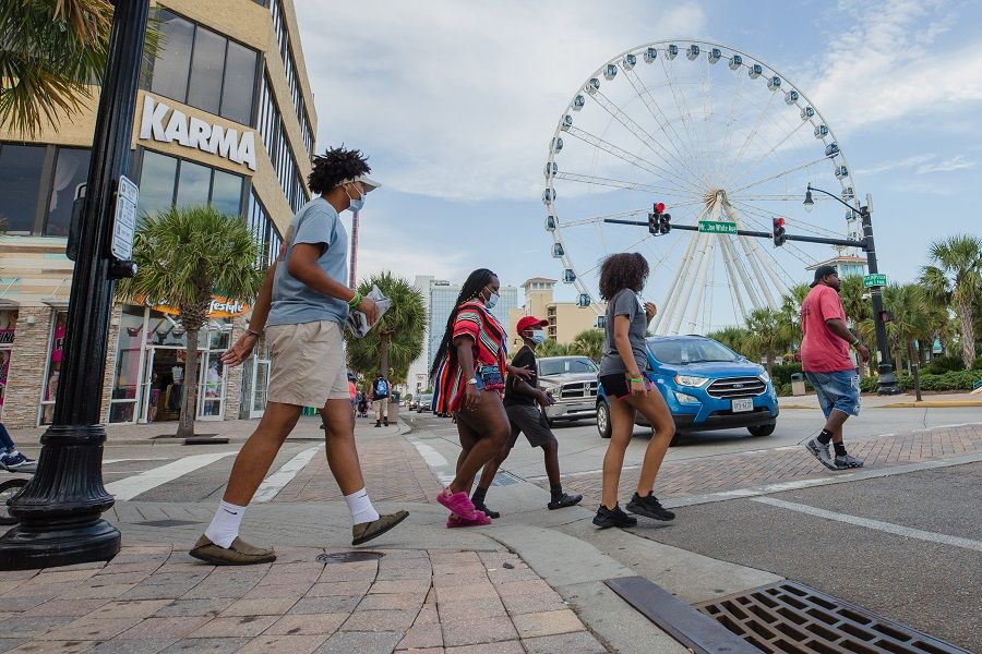 Pedestrians wearing protective mask cross a street in Myrtle Beach, South Carolina, US, on 19 August 2020. (Micah Green/Bloomberg)