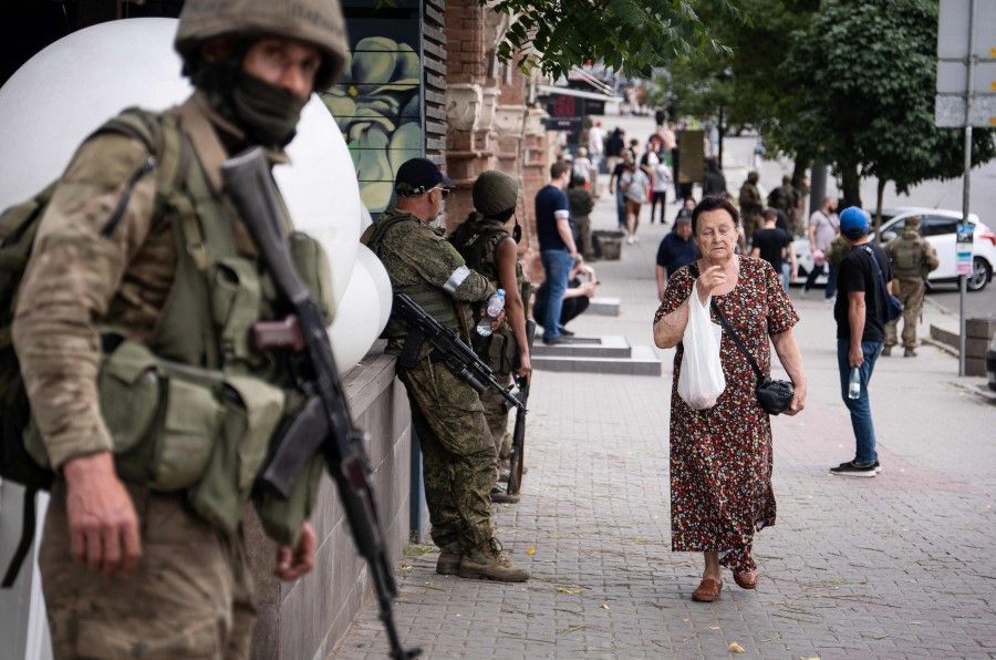 A local resident walks past members of Wagner group in Rostov-on-Don, on 24 June 2023. (Roman Romokhov/AFP)