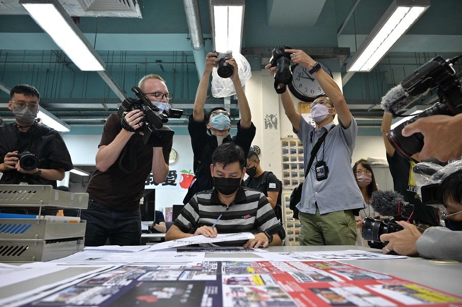 Members of the press take photos as executive editor-in-chief Lam Man-Chung (centre) proofreads the next day's Apple Daily newspaper before it goes to print for what was announced earlier in the day to be for the last time, in Hong Kong, China, late on 23 June 2021. (Anthony Wallace/AFP)