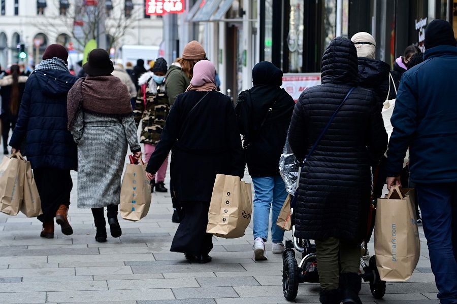 People carrying several shopping bags walk on a street in Brussels, Belgium, on 4 January 2021 (Laurie Dieffembacq/Belga/AFP)