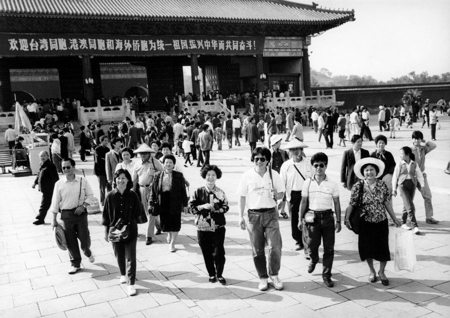 Taiwanese tourists on a trip to Beijing, 1998. The banner in the background welcomes ethnic Chinese from Taiwan, Hong Kong and Macau as well as other parts of the world to work together for the reunification of the motherland and revitalise China.