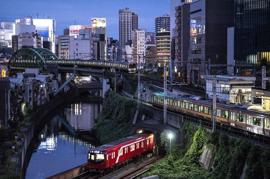 Trains travelling on three different rail lines are seen at dusk near Ochanomizu station in Tokyo, Japan, on 26 September 2021. (Charly Triballeau/AFP)