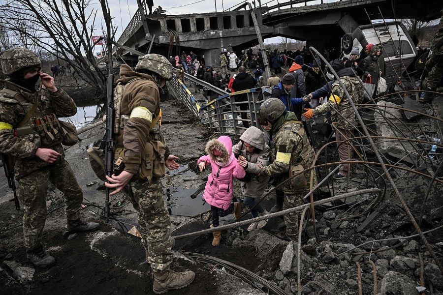 People cross a destroyed bridge as they evacuate the city of Irpin, northwest of Kyiv, during heavy shelling and bombing on 5 March 2022. (Aris Messinis/AFP)