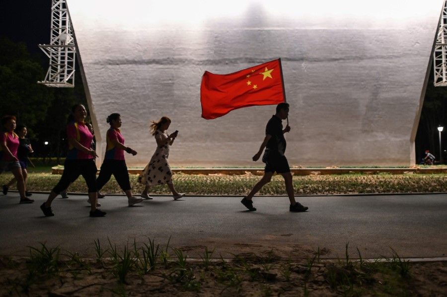 In this photo taken on 4 September 2020, a man walks with the Chinese national flag in a park next to the Yangtze River in Wuhan. (Hector Retamal/AFP)
