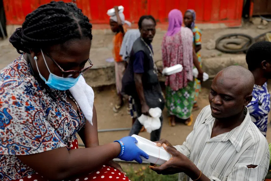 A volunteer distributes cooked food and water to the underprivileged and homeless, as Ghana enforces a partial lockdown in Accra and Kumasi in efforts to slow the spread of the coronavirus in Accra, Ghana, April 4, 2020. (Francis Kokoroko/REUTERS)