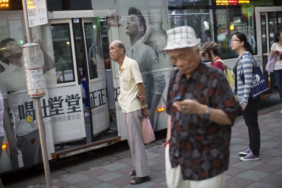 Pedestrians wait at a bus stop near Taipei Main Station in Taipei, Taiwan, on 24 July 2013. (Bloomberg)
