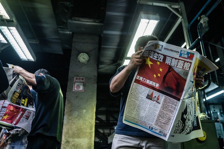 An employee proofreads a copy of the Apple Daily newspaper, published by Next Media, at the company's printing facility in Hong Kong, early on 1 July 2020. The headline reads: "Birth of Evil Law, Death of Two Systems." (Lam Yik/Bloomberg)