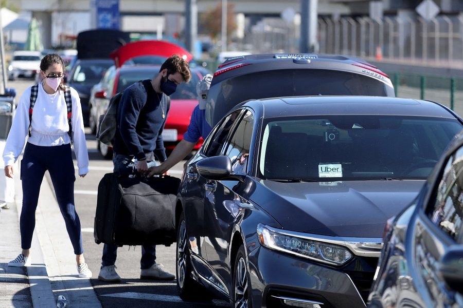 Passengers wait for Uber ride-share cars after arriving at Los Angeles International Airport in Los Angeles, California, US, on 10 July 2022. (David Swanson/Reuters)