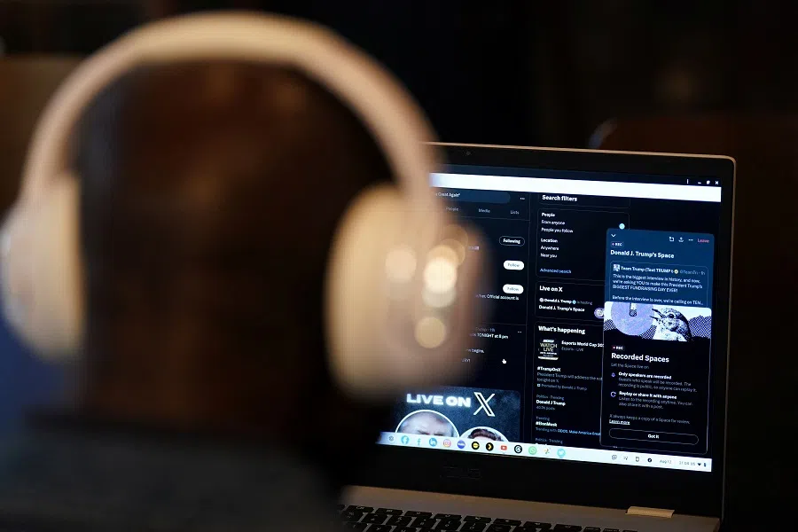 A person listens on a laptop as billionaire entrepreneur Elon Musk interviews Republican presidential candidate and former US President Donald Trump on the X social media network, in New York City, US, on 12 August 2024. (Adam Gray/Reuters)