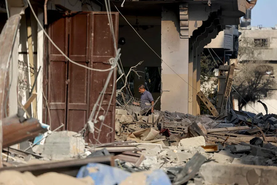 A Palestinian man walks amid the rubble of a building hit in an Israeli air strike on 13 October 2023. (Mohammed Abed/AFP)
