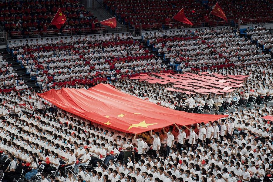 This photo taken on 26 September 2020 shows first-year students holding a Chinese flag during a commencement ceremony at Wuhan University in Wuhan, Hubei, China. (STR/AFP)