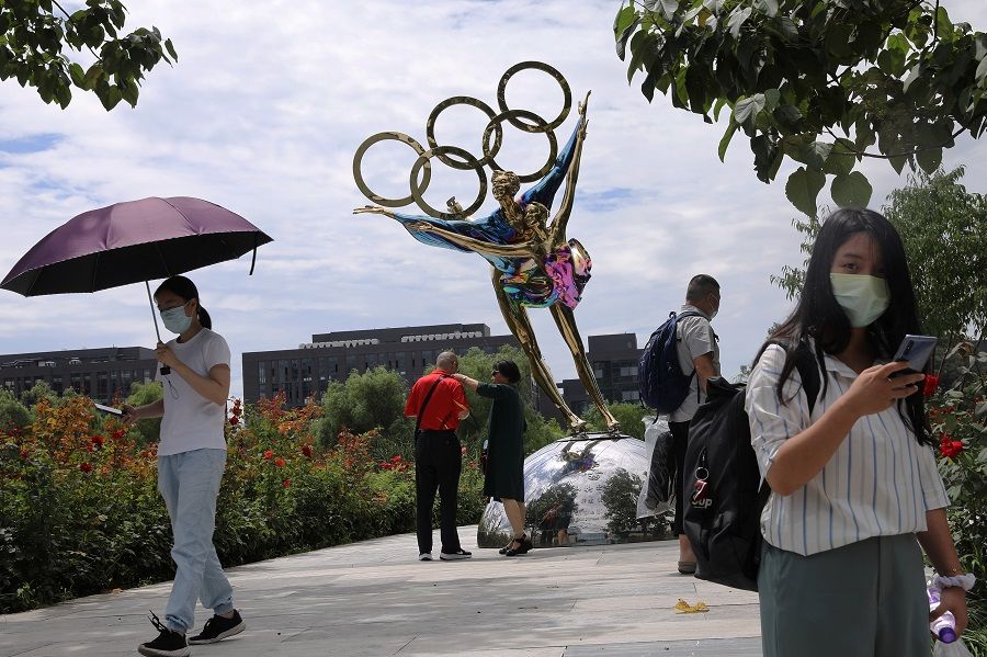Visitors are seen next to a sculpture featuring skates outside the headquarters of the Beijing Organising Committee for the 2022 Olympic and Paralympic Winter Games in Beijing, China, 30 July 2021. (Tingshu Wang/Reuters)