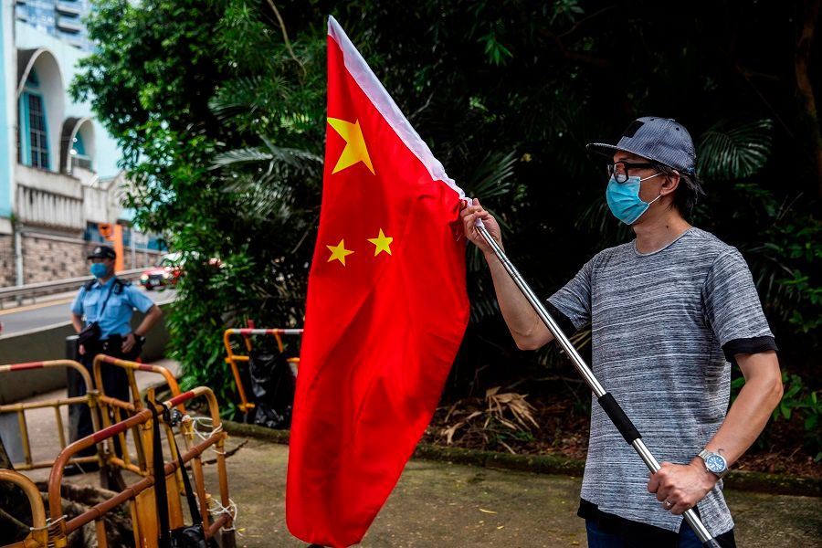 A protester (right) demonstrates outside the US consulate in Hong Kong on 8 August 2020 after the US applied sanctions on Hong Kong Chief Executive Carrie Lam and other top officials in response to Beijing enacting a national security law on the city. (Isaac Lawrence/AFP)