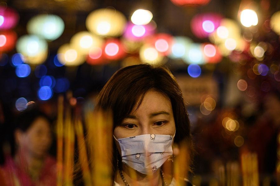 A woman wears a face mask as she burns incense and prays at the Wong Tai Sin Temple to mark the Lunar New Year of the Rat in Hong Kong on 24 January 2020. (Philip Fong/AFP)
