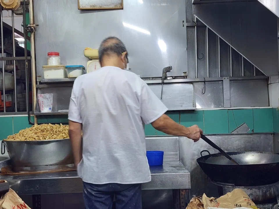The owner of the sachima stall in Chinatown stirs his wok. (SPH Media)