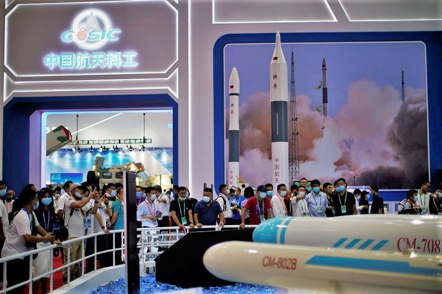 Visitors look at models of military equipment displayed at the China Aerospace Science & Industry Corporation Limited (CASIC) booth at Airshow China, in Zhuhai, Guangdong province, China, 28 September 2021. (Aly Song/Reuters)