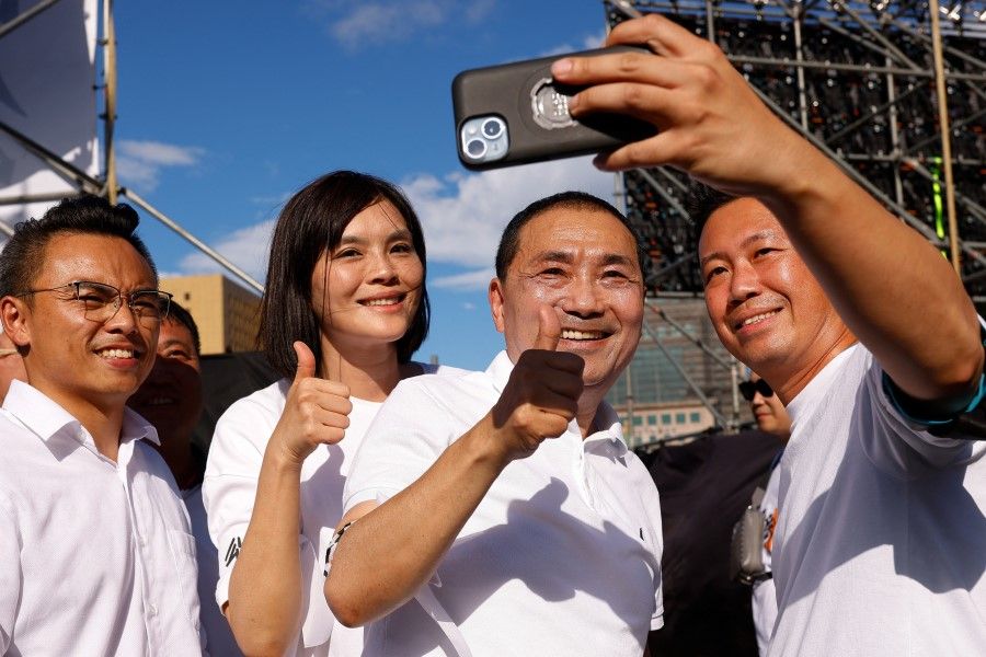 Supporters take a selfie with Hou You-yi of Taiwan's main opposition party the Kuomintang who also made a speech on stage at the rally for legal reform and against high real estate prices in Taipei, Taiwan, on 16 July 2023. (Ann Wang/Reuters)