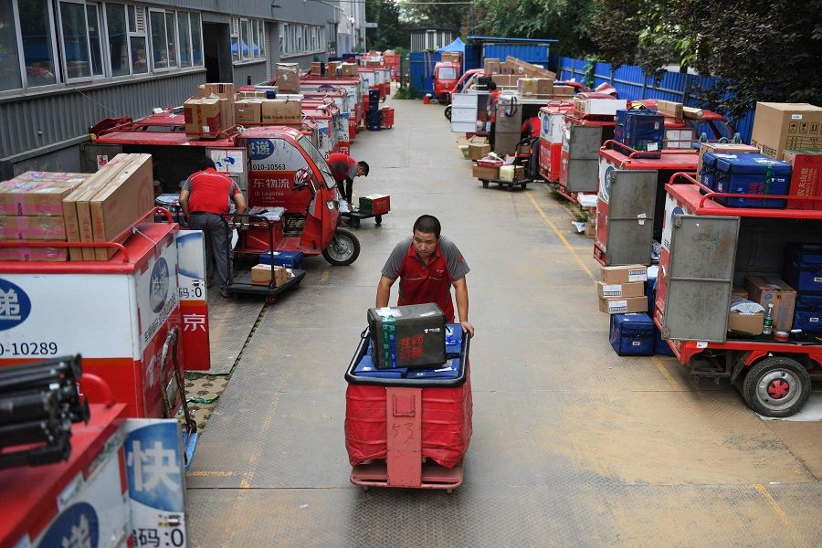 A worker hauls packages to delivery carts at a JD.com distribution center in Beijing on 16 July 2020. (Greg Baker/AFP)
