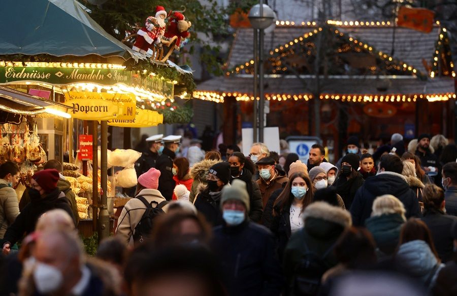 People wearing face masks visit the Christmas market, in Frankfurt, Germany, 22 November 2021. (Kai Pfaffenbach/Reuters)