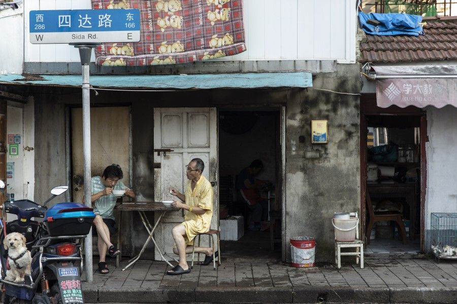 Two men have their breakfast on the street in an older neighborhood in Shanghai, China on 30 August 2021. Chinese President Xi Jinping chaired a high-level meeting that "reviewed and approved" measures to fight monopolies, battle pollution and shore up strategic reserves, all areas that are crucial to his government's push to improve the quality of life for the nation's 1.4 billion people. (Qilai Shen/Bloomberg)